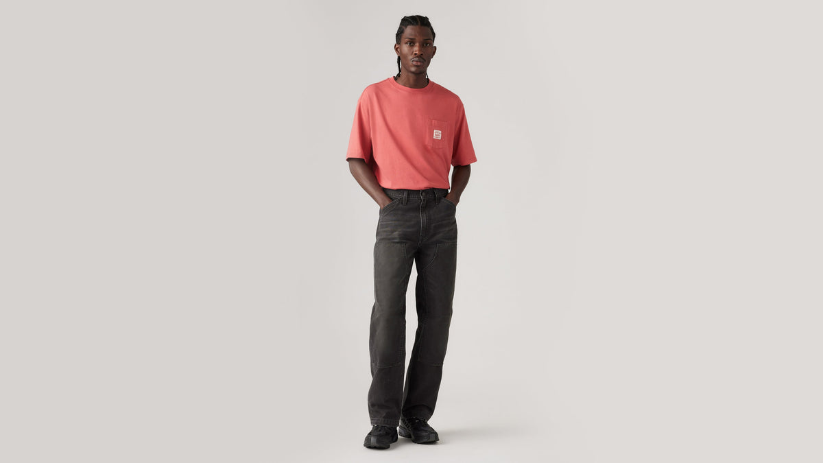 Model wearing dark gray Levi’s 568 Double-Knee pants with tee, front view
