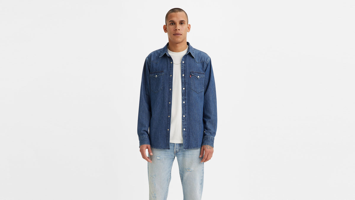 Male model in a blue Levi's denim shirt & ripped jeans, facing the camera