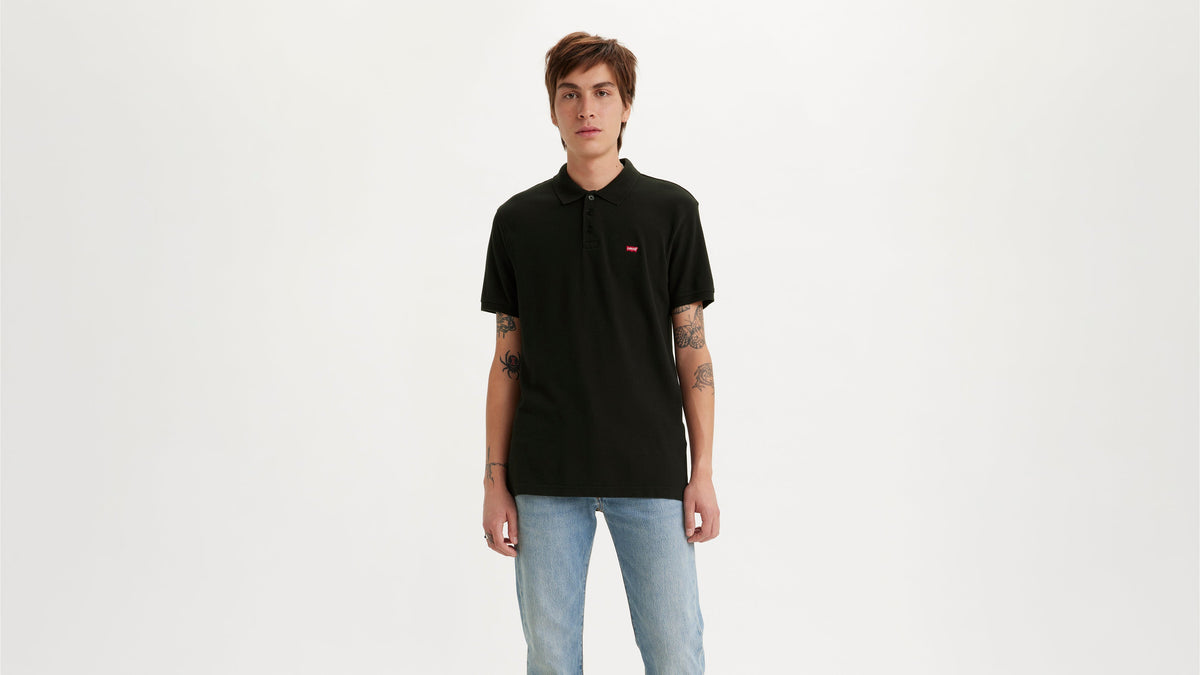 Front view of Levi's black housemark polo shirt on model, paired with faded jeans
