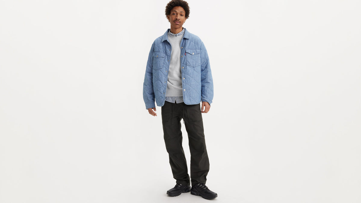 Front view of a man in a light blue jacket, grey sweatshirt, & Levi's Surplus pants