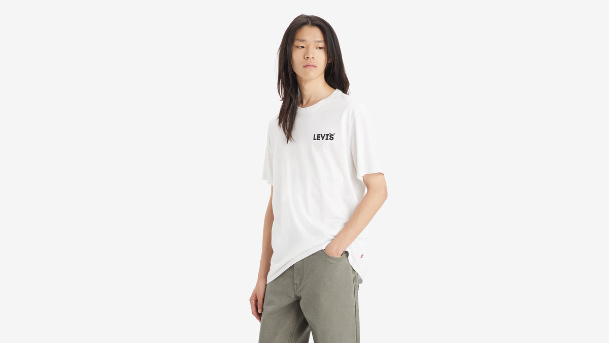 Front view of man in white Levi’s Relaxed Fit Short-Sleeve Graphic T-Shirt & grey pants