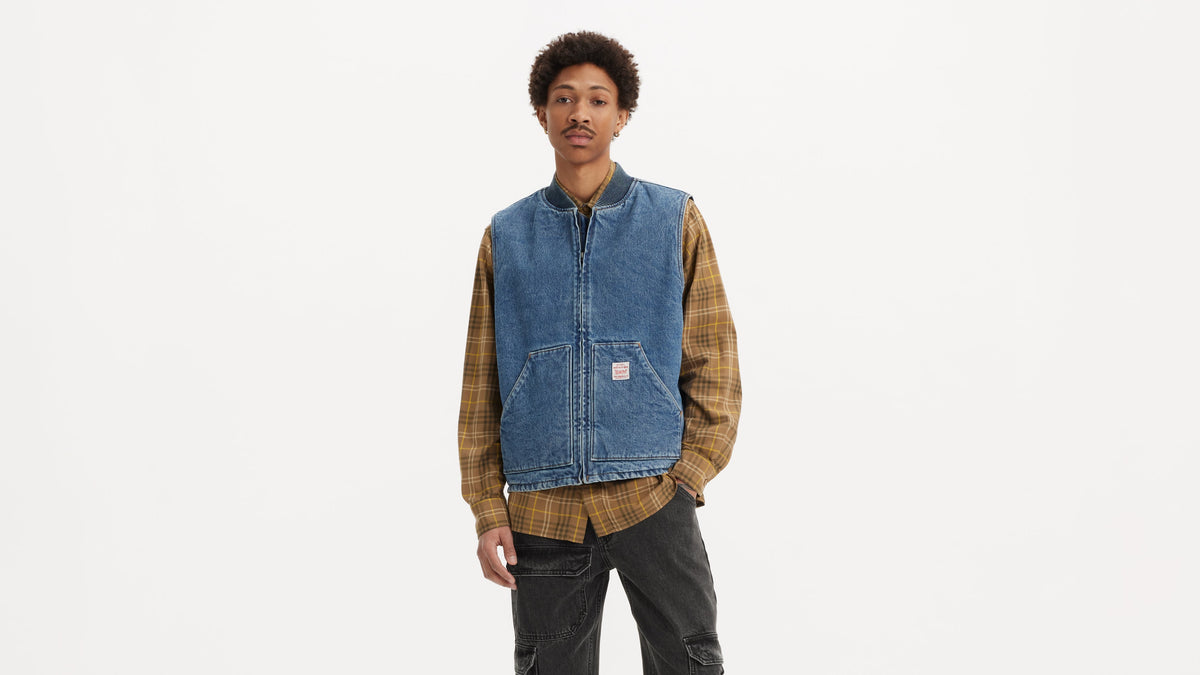 Man wears Levi’s blue sansome vest over brown check shirt and black cargo pants