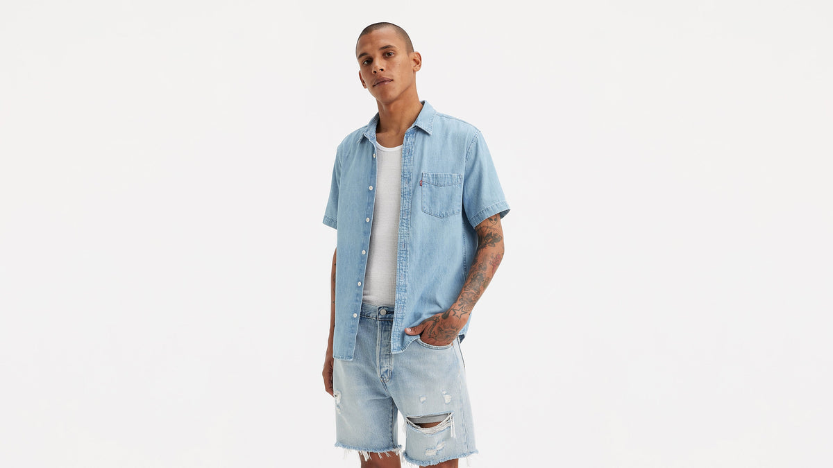 Front view of a man in Levi's Classic shirt & ripped shorts with tattoos visible