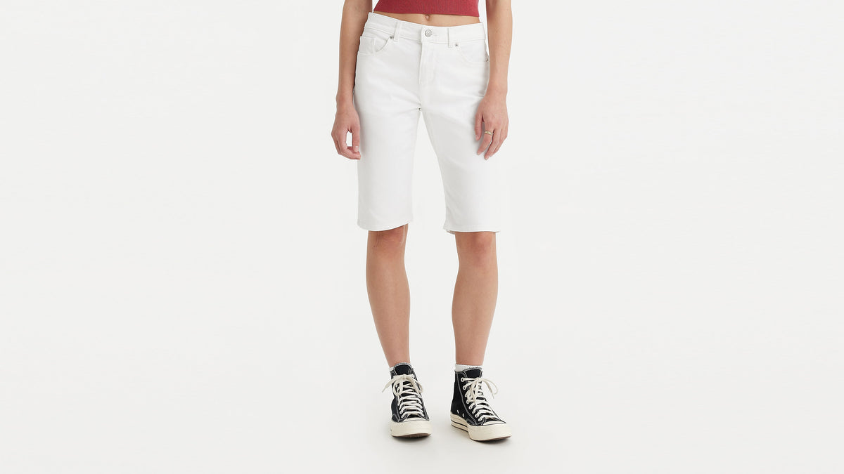 Half-body shot of a woman in white Levi’s bermuda shorts with sneakers