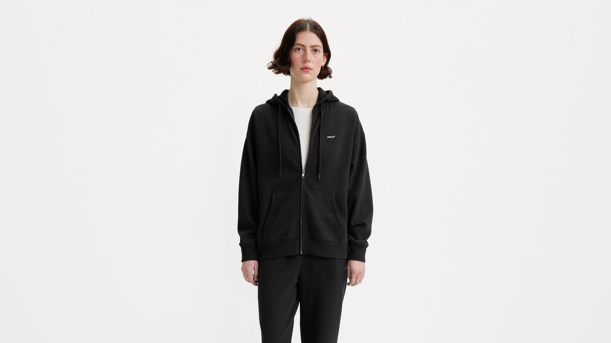 Model wearing black Levi's zip hoodie with front pockets & white chest logo
