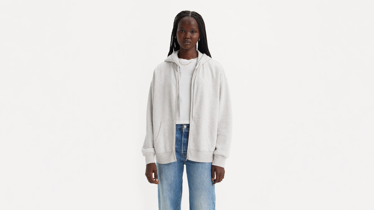 Model in grey zip hoodie worn open over white tee & jeans, facing front
