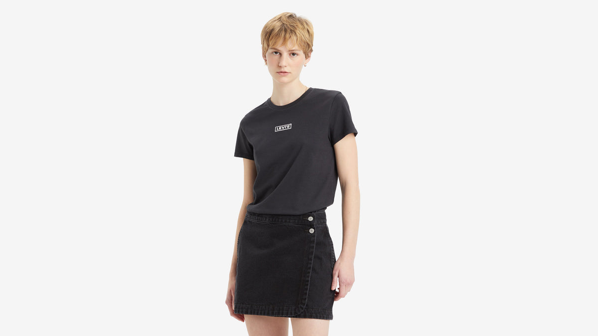 Front view of a woman in black Levi's Tee tucked in black mini skirt
