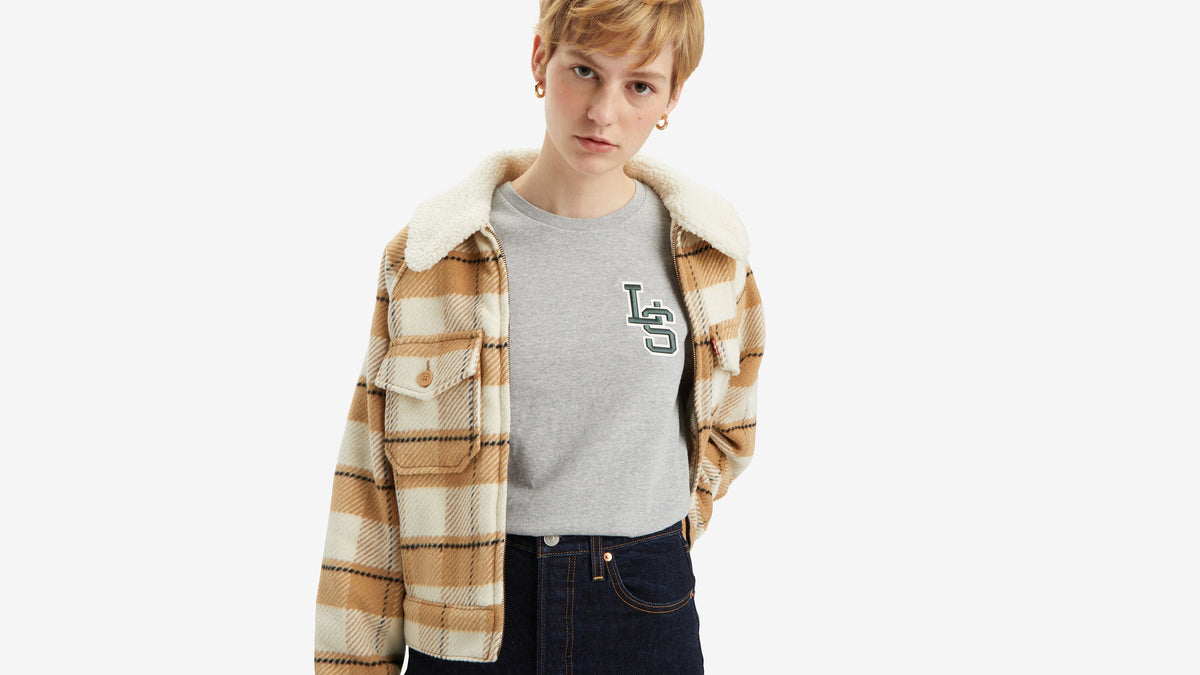 Woman in grey Levi’s tee and tan plaid jacket