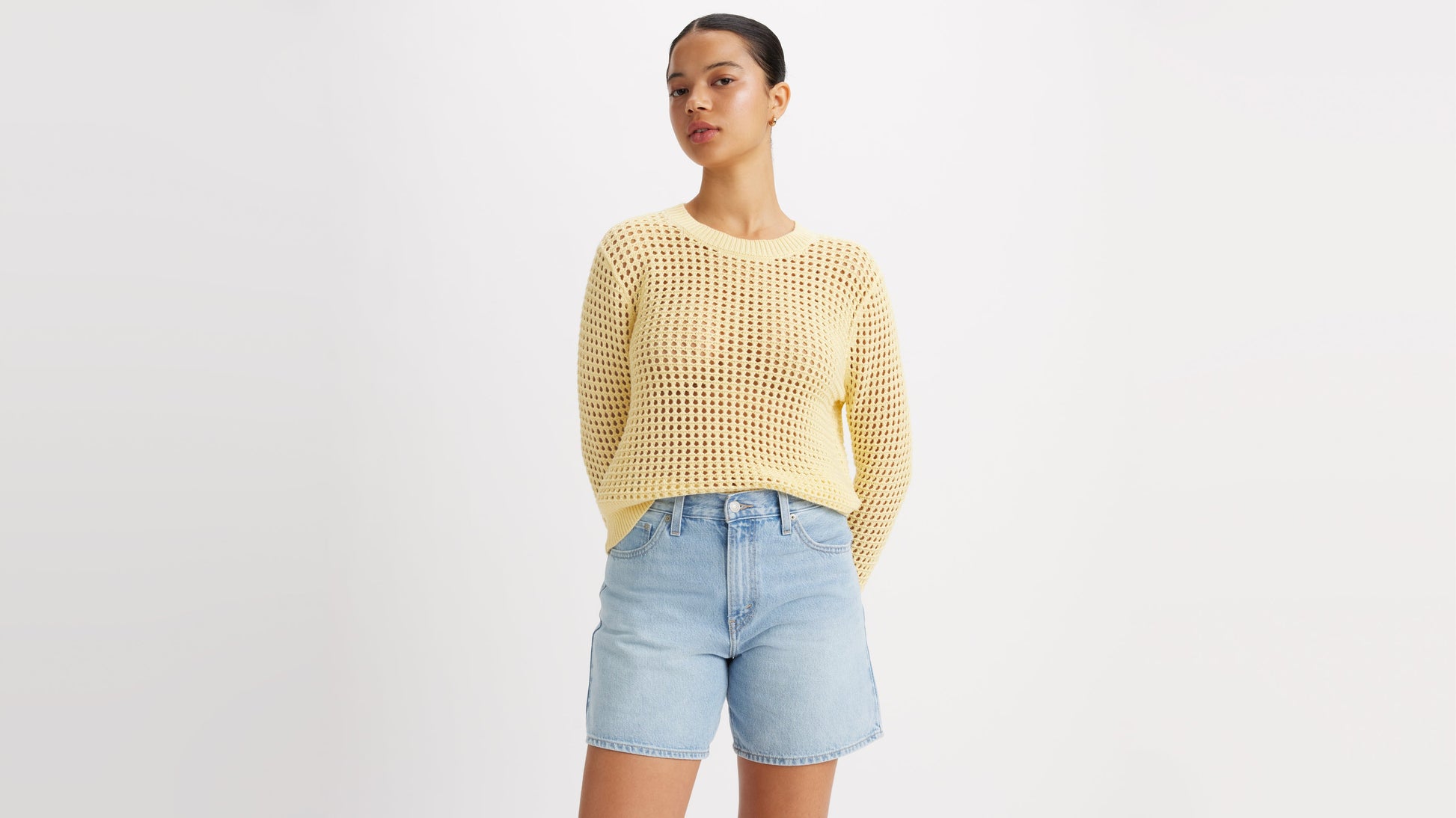 Woman in a knitted yellow top and casual denim shorts