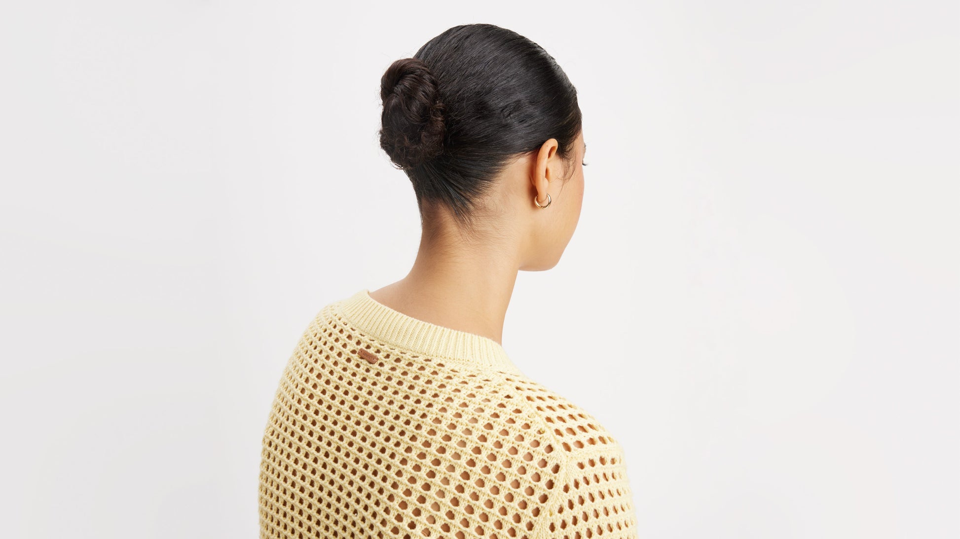 Back view of a woman wearing a cream crochet sweater