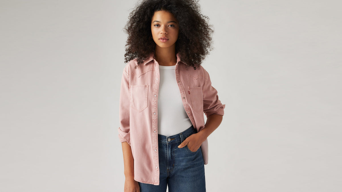 Woman in pink Levi’s shirt over white tank and jeans