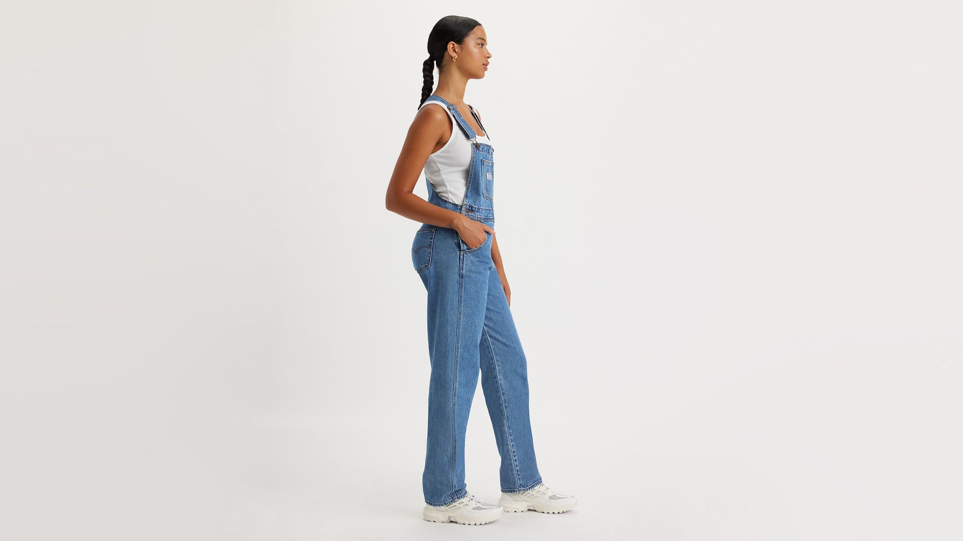 Side view of model in blue overalls and white tank