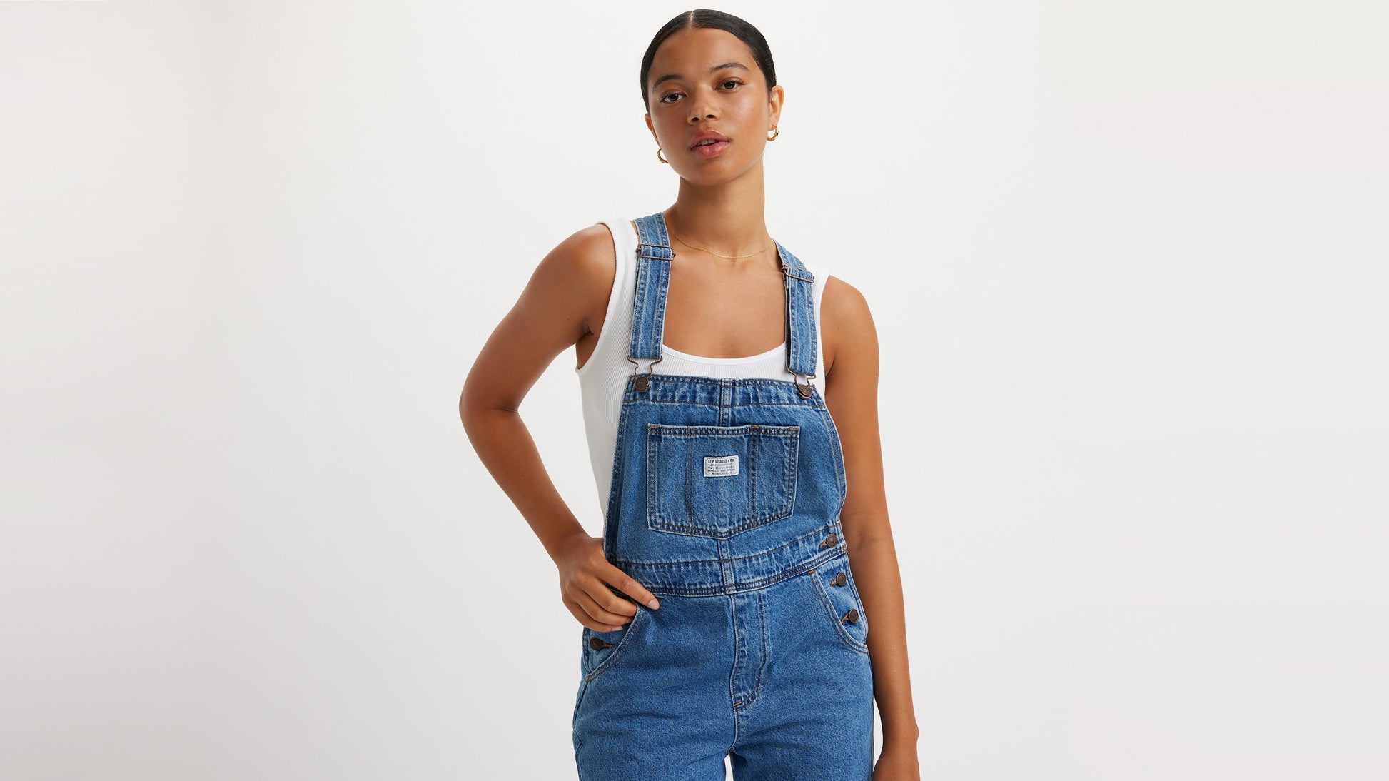 Model in blue denim overalls and sleeveless top