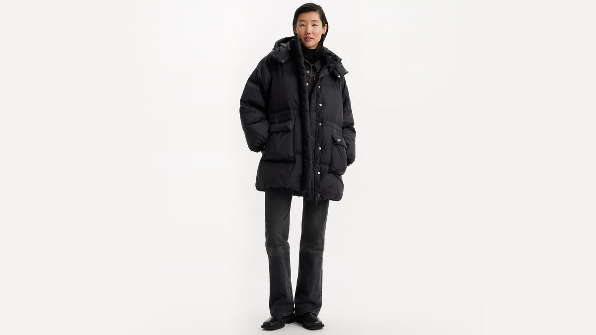 Woman in black oversized puffer coat with snap buttons and hood