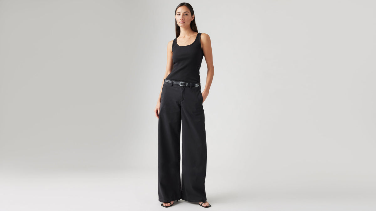 Woman in black tank top and black XL chino pants with a belt, front view
